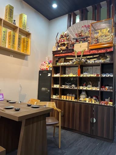 Wooden dining table beside shelves of ceramics and sake bottles