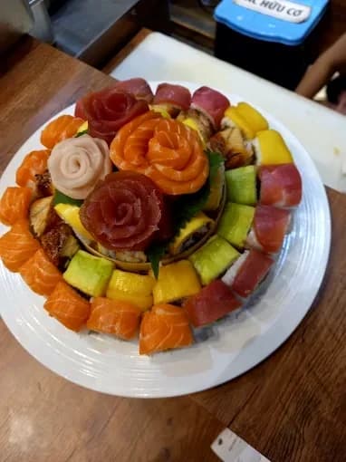 Round platter of sushi rolls with fish arranged like flowers
